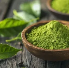 Green tea powder in a wooden bowl with fresh leaves