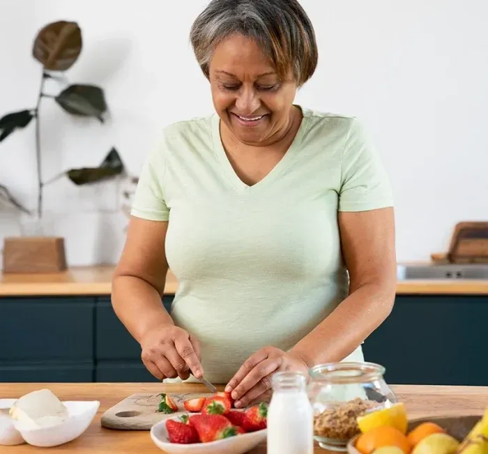 An older woman chopping fresh vegetables at a kitchen counter